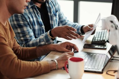 Ofis masasında dökümanları tartışan kıdemli geliştiricilerin kırpılmış resmi