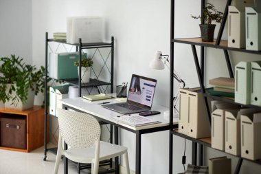 Evden çalışan girişimci masası, klasörlü raflar, dizüstü bilgisayar ve dekorasyon için bitki