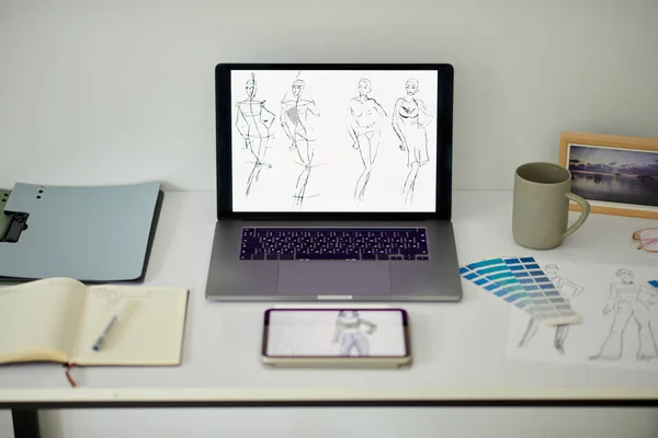 Laptop with fashion sketches on screen on desk of designer