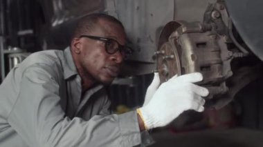 Servis atölyesinde arabayı incelerken Afrikalı Amerikalı bir uzmanın orta boy görüntüsü.