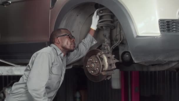 Mellemlangt Skud Sort Mekaniker Undersøge Hjulet Foråret Minivan Arbejder Bil – Stock-video