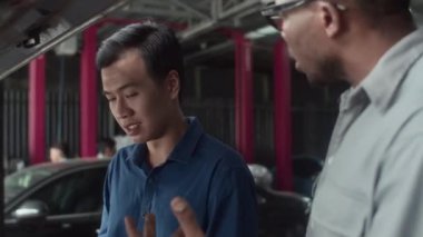 Benzin istasyonundaki erkek otomobil sahibine sızıntıyı açıklayan uzman görüntüsünü eğ.