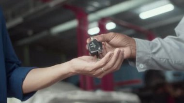 Erkek tamircinin arabanın anahtarlarını sahibine vermesine ve servis merkezinde el sıkışmasına yakın durun.