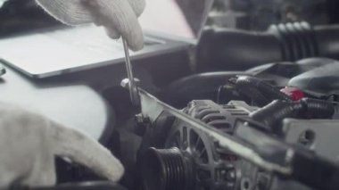 Servis istasyonunda müşterinin arabasını tamir ederken İngiliz anahtarı kullanan bir uzmanın ellerini kapat