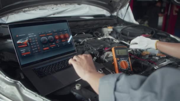 Felismerhetetlen Szakemberek Közelről Ellenőrzik Motorháztető Alkatrészek Munkáját Multiméterrel Alkalmazással Laptopon — Stock videók