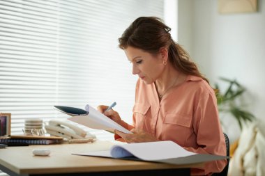 Ofiste çalışırken rapor edilen verileri düzelten ciddi olgun bir iş kadını