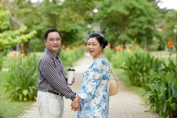 上了年纪的夫妻手牵着手 在公园里散步时又回到镜头前 — 图库照片