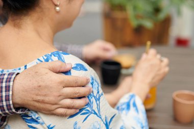 Kahvecide kahve içerken karısına sarılıyor.