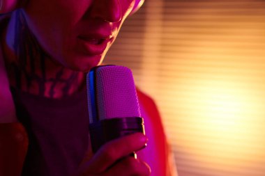 Karaoke yaparken neon ışıkta duran genç adamın kırpılmış görüntüsü