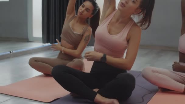 在室内瑜伽课上做侧弯运动的多民族女运动员的倾斜镜头 — 图库视频影像