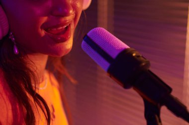 Yeni parça kaydederken mikrofonda şarkı söyleyen genç bir kadının yakın plan görüntüsü