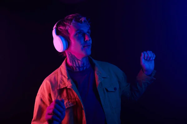 stock image Young man dancing in neon light to music in headphones