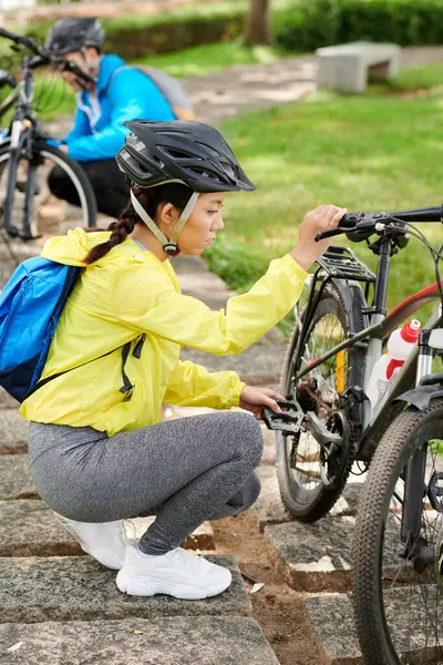 Серйозна Молода Спортсменка Шоломі Перевіряє Свій Велосипед Перед Поїздкою Щоб — стокове фото