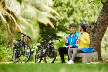 Neşeli sevgili, tatlı su içiyor ve parkta ağacın altında konuşuyor.