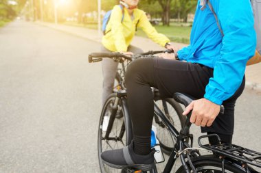 Şehirde arkadaşlarıyla bisiklet sürerken tayt ve şort giyen bir adamın kırpılmış görüntüsü.