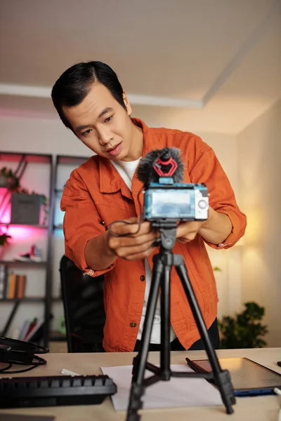 年轻的亚洲男子站在相机后面 调整相机设置 在家里录制视频博客 — 图库照片