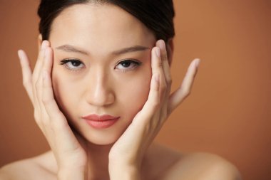 Ciddi bir Vietnamlı kadının yüzü kusursuz yumuşak tenine dokunuyor ve kameraya bakıyor.