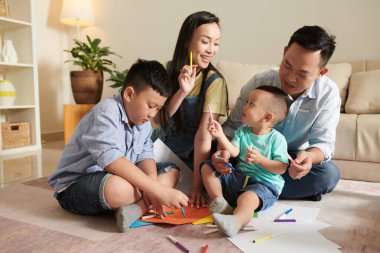 Dört kişilik mutlu bir aile birlikte resim çiziyor.