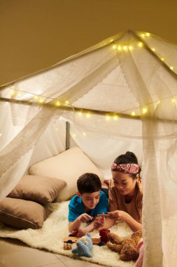 Anne, oğlunun kırık tahta arabayı tamir etmesine yardım ediyor.