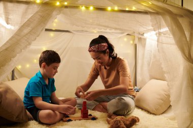Gururlu çocuk oyuncak bloklardan nasıl kule inşa ettiğini annesine gösteriyor.