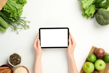 Tablet bilgisayarlı, boş ekranlı, alışveriş masalı bir kadının elleri.