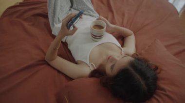 Z jenerasyonundan bir kadının hafta sonu evde dinlenirken cep telefonundan mesajları kontrol etmesi