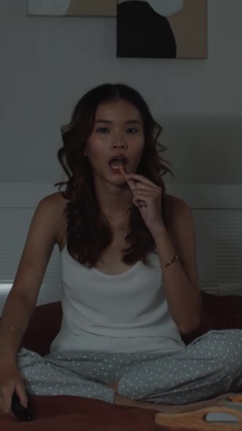Pionowe Ujęcie Kobiety Genu Jedzącej Chipsy Oglądającej Telewizję Siedzącej Łóżku — Wideo stockowe