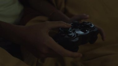 Gecenin geç saatlerinde evde oyun oynarken joystick kullanan tanınmayan bir kadının ellerini kapat.