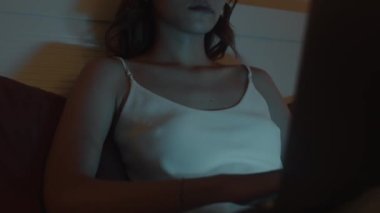 Asyalı serbest çalışan bir kadının gece geç saatlerde dizüstü bilgisayarla yatakta oturmasını çek.