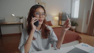Asyalı iş kadınının iş arkadaşını ararken laptopun önünde otururken görüntüyü büyüt, evden çalışıyor.