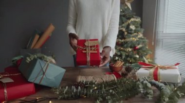 Tarçın çubuklarıyla süslenmiş kırmızı kağıda sarılı, elinde tanınmayan bir kadının hediyesini yakınlaştır.