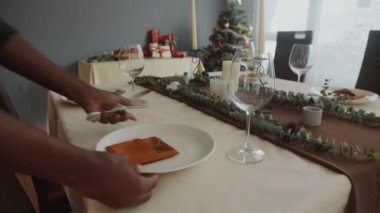 Siyah ırktan bir kadının ellerini kapayın Noel kutlaması için sofraya tabak koyun.
