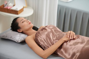 Sakin bir kadın, spa salonundaki kanepede dinleniyor. Ustasının ameliyata başlamasını bekliyor.