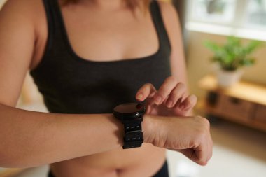 Spor sütyenli formda genç bir kadın akıllı adam bildirimlerini kontrol ediyor.