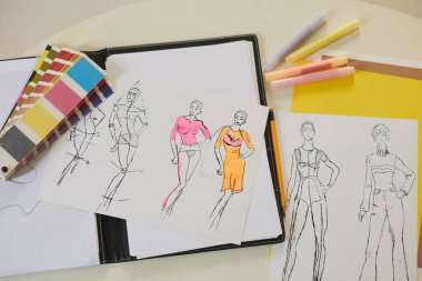 Moda çizimleri, renk paleti ve moda tasarımcısının masasındaki keçeli kalemler.