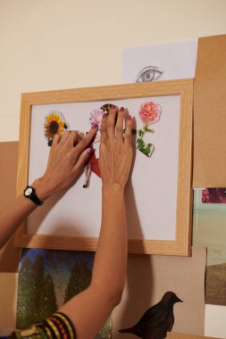 Kolaj ve yapıştırma üzerine çalışan kadın ressamların elleri kağıt üzerine kesilmiş resimler ve fotoğraflar