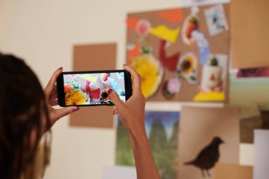 İlham için yaptığı çiçek kolajını fotoğraflayan kadın sanatçı.