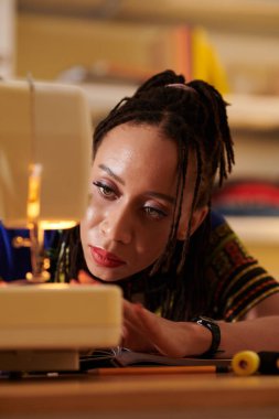 Terzi kadın dikiş makinesinin neden çalışmadığını anlamaya çalışıyor.