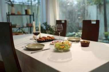 Yemek masasında bir bardak şarap ve aperatifler.