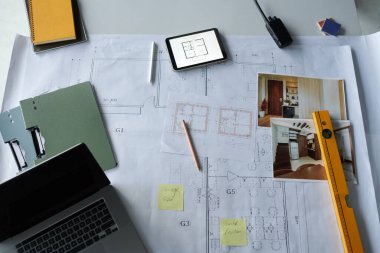 Mimar veya iç mimarın masasında planlar, fotoğraflar ve dizüstü bilgisayarlar