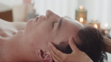 Masözün elleri kapalıyken spa salonundaki erkek müşteriye kafa ve tapınak masajı yapıyor.