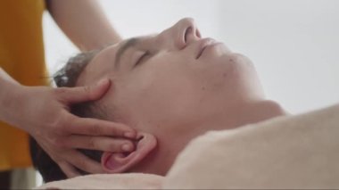 Salondaki erkek müşteriye yüz gerdirme masajı yapan kadın uzmanın ellerini kapatın.