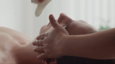 Salondaki işlem sırasında erkek müşteriye masaj yaparken gua sha aracını kullanarak masajı kapat