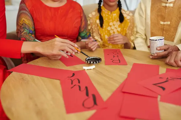 Hands of family members writing calligraphy couplets when preparing for Lunar New Year
