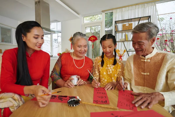Family members writing inspiring couplets for Lunar New Year celebration
