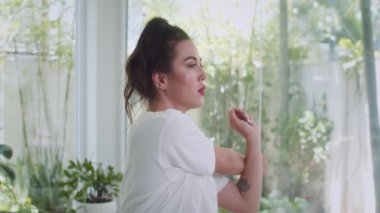 Beyaz tişörtlü gülümseyen genç bir sporcunun portresi. Antrenman sırasında vücut büküyor ve kameraya bakıyor.