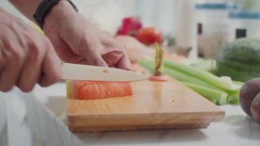 Öğle yemeği için salata yaparken tahta tahtada keskin bir bıçakla havuç kesen tanınmayan bir adamın ellerini kapatın.