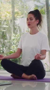 Kafkasyalı bir kadın Lotus 'un önünde oturmuş evde yoga yaparken meditasyon yaparken poz veriyor.