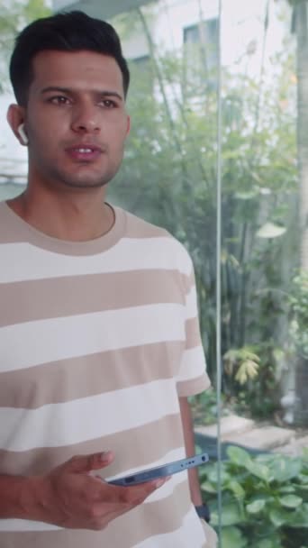 Vertical Lentidão Jovem Indiano Vestindo Fones Ouvido Enquanto Fala Telefone — Vídeo de Stock