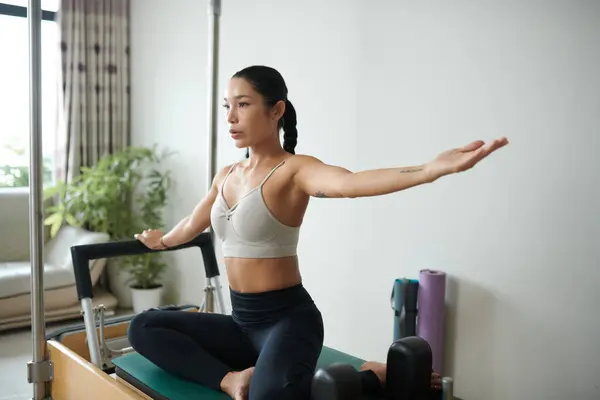 stock image Fit young woman doing side bend when exercising in special machine